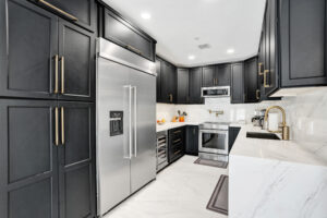 Luxury kitchen with custom black cabinets, quartz counters, and stainless steel appliances in Unit A, Wilton Manors.