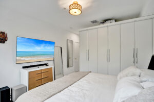 Bedroom with custom white wardrobes and wall-mounted TV in Unit A, 624 NE 29th Drive.